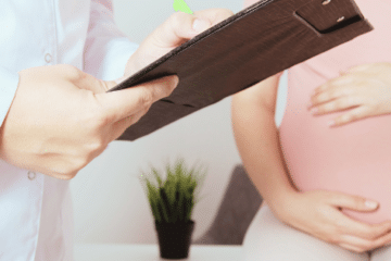 Anemic pregnant woman wearing pink consulting a doctor