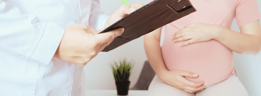 Anemic pregnant woman wearing pink consulting a doctor